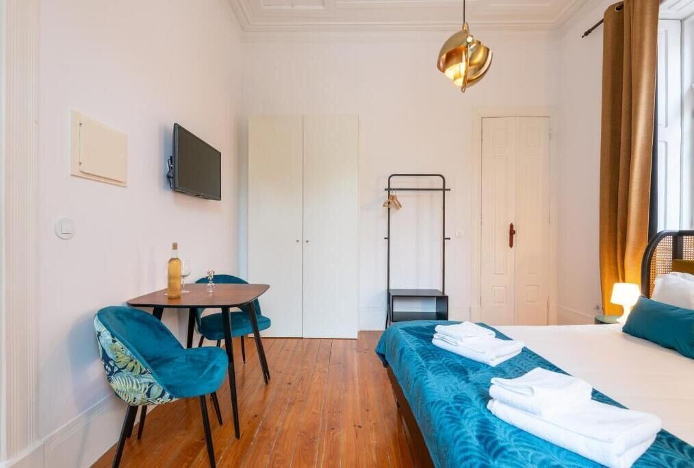 A hotel room with a bed, a desk, a chair, a television, a wardrobe, and a hanging rack.