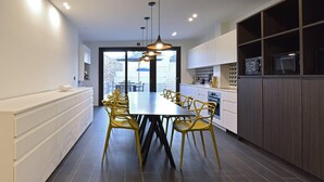 A modern kitchen with a central island, yellow chairs, and a dining table.