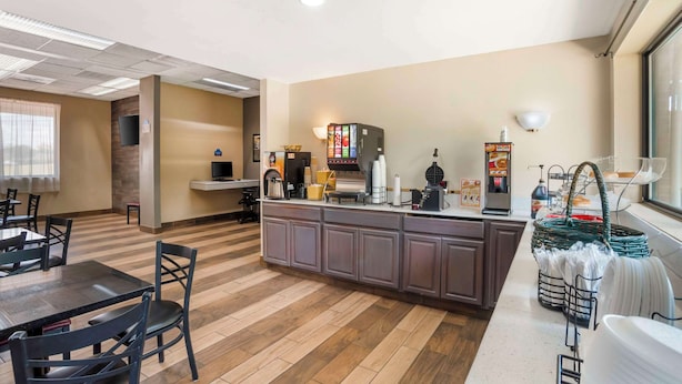 Une chambre d’hôtel avec un plancher en bois, une kitchenette, un coin repas avec une table et des chaises, et une grande fenêtre.