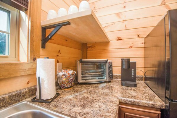 A compact kitchen with a toaster, coffee maker, and a sink.