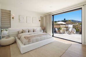 A modern bedroom with a large bed, a view of the outdoors, and a balcony with seating. - Scandinavi Inn  (Chelan)