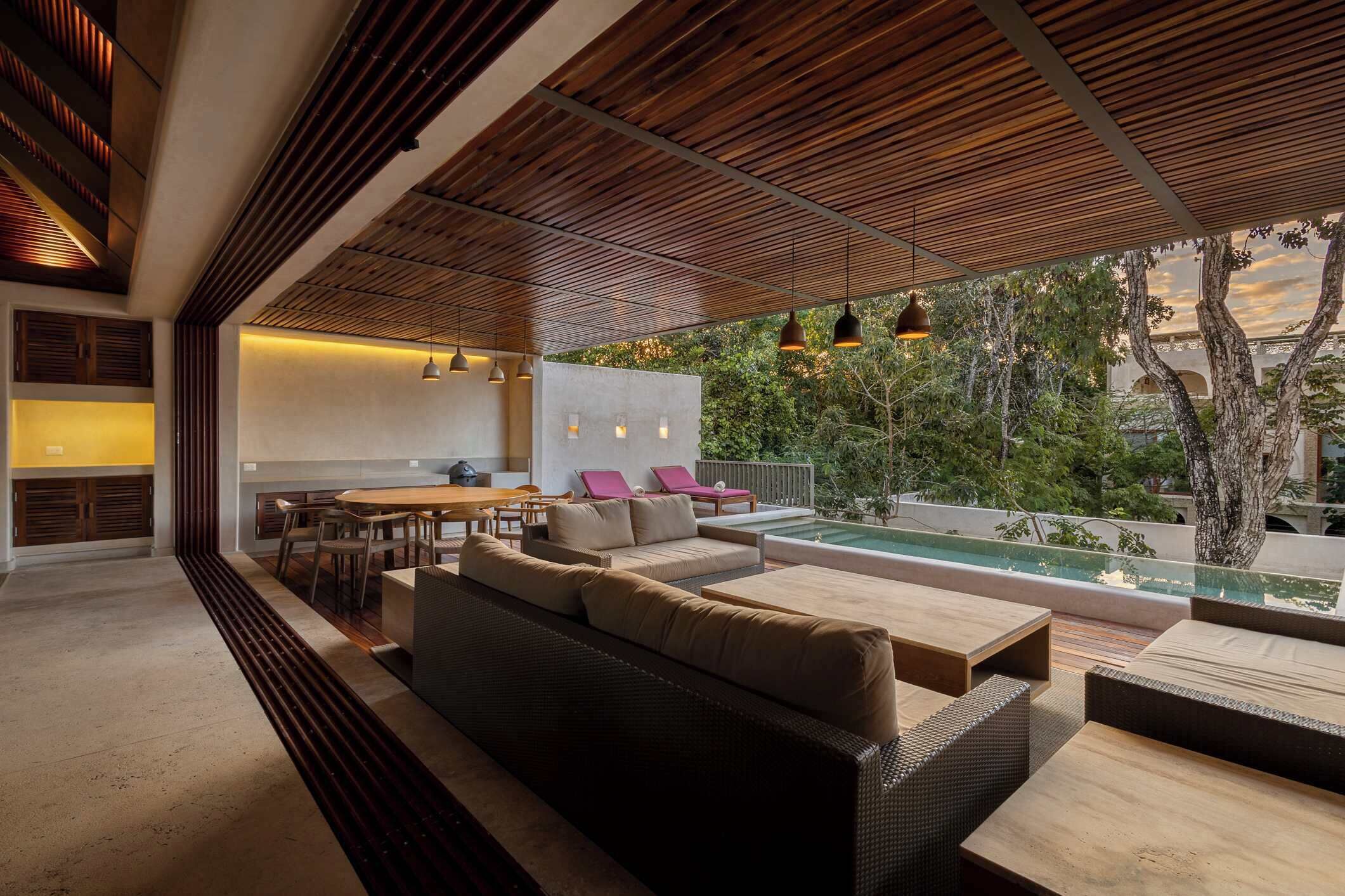 A modern outdoor living area with a pool, wooden ceiling, and seating arrangements.