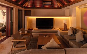 A modern living room with a flat-screen TV, comfortable seating, and a ceiling fan.