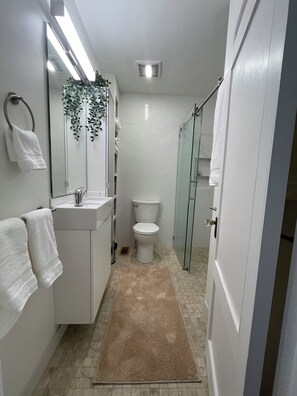 Een moderne badkamer met toilet, wastafel en douchecabine van glas.