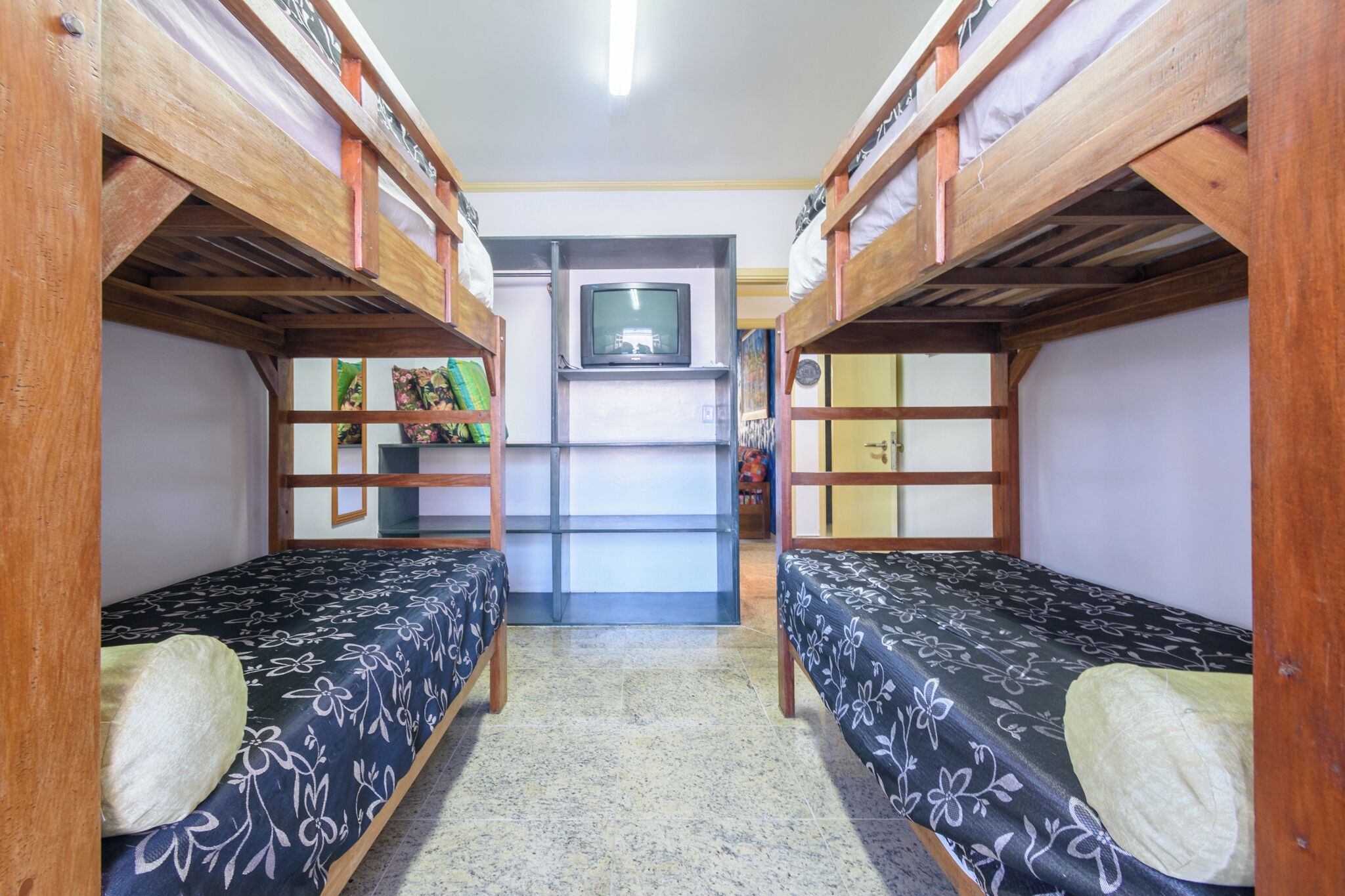 Una camera del dormitorio con letti a castello, una televisione e un piccolo ripiano con libri e oggetti decorativi.