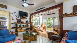 A well-lit living room with a television, wooden furniture, and a view of the outdoors. - Casa piscina e lazer 50m praia Lagoinha (Ubatuba)