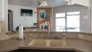A kitchen with a large sink, two pendant lights, and a window with a view of the outdoors. - Sleeps 25 | Theater Room | Near Roaring Springs | Large Meridian Home (Meridian)