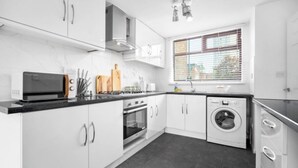 A modern kitchen with white cabinets, a microwave, stove, oven, and a washing machine. - STYLISH-BIRMINGHAM central home!!! (Birmingham)