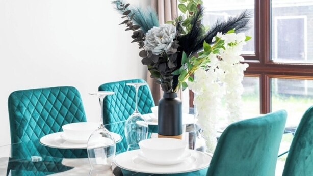 A dining table with teal chairs, clear glassware, and a vase with white flowers and green foliage. - STYLISH-BIRMINGHAM central home!!! (Birmingham)
