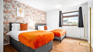 A bedroom with two beds, a brick-patterned wall, and a window with curtains. - STYLISH-BIRMINGHAM central home!!! (Birmingham)
