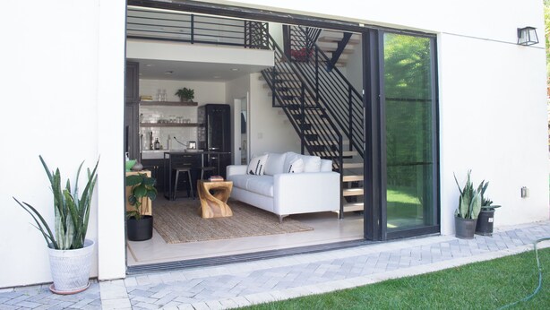A modern interior with a white sofa, a wooden coffee table, and a staircase leading to an upper level.