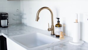 A kitchen with a white sink, wooden shelves, and a coffee machine.
