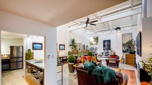 A spacious living area with a leather sofa, a red patterned rug, and a ceiling fan.