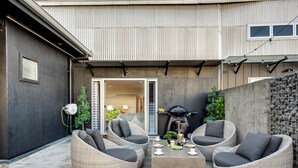 A patio area with wicker furniture, a coffee table, and a grill.