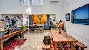 A spacious kitchen with modern appliances, a dining area with a wooden table and bench, and a large painting of a pier on the wall.