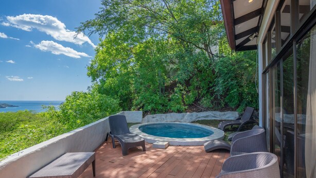Une terrasse dotée d’un jacuzzi, de fauteuils en osier et d’un banc offrant une vue panoramique.