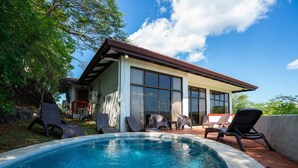 Une maison moderne dotée d’une piscine, de mobilier d’extérieur et de grandes fenêtres.