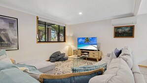 A living room with a television, a sofa, a coffee table, and a lamp. - Coastal Haven in Long Beach (Long Beach)