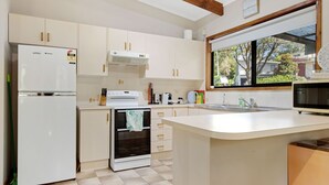 A kitchen with a refrigerator, stove, oven, microwave, and a large window. - Coastal Haven in Long Beach (Long Beach)