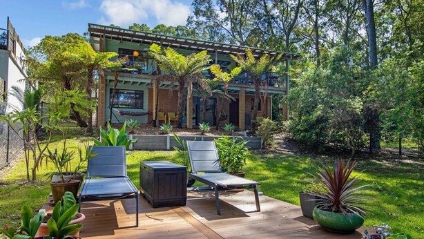 A modern house with a patio, outdoor furniture, and lush greenery. - Coastal Haven in Long Beach (Long Beach)
