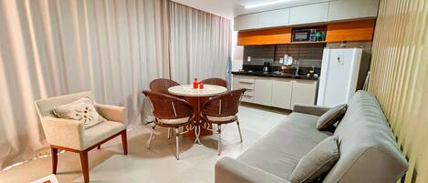 A compact living space with a dining area, a sofa, a chair, and a kitchenette.