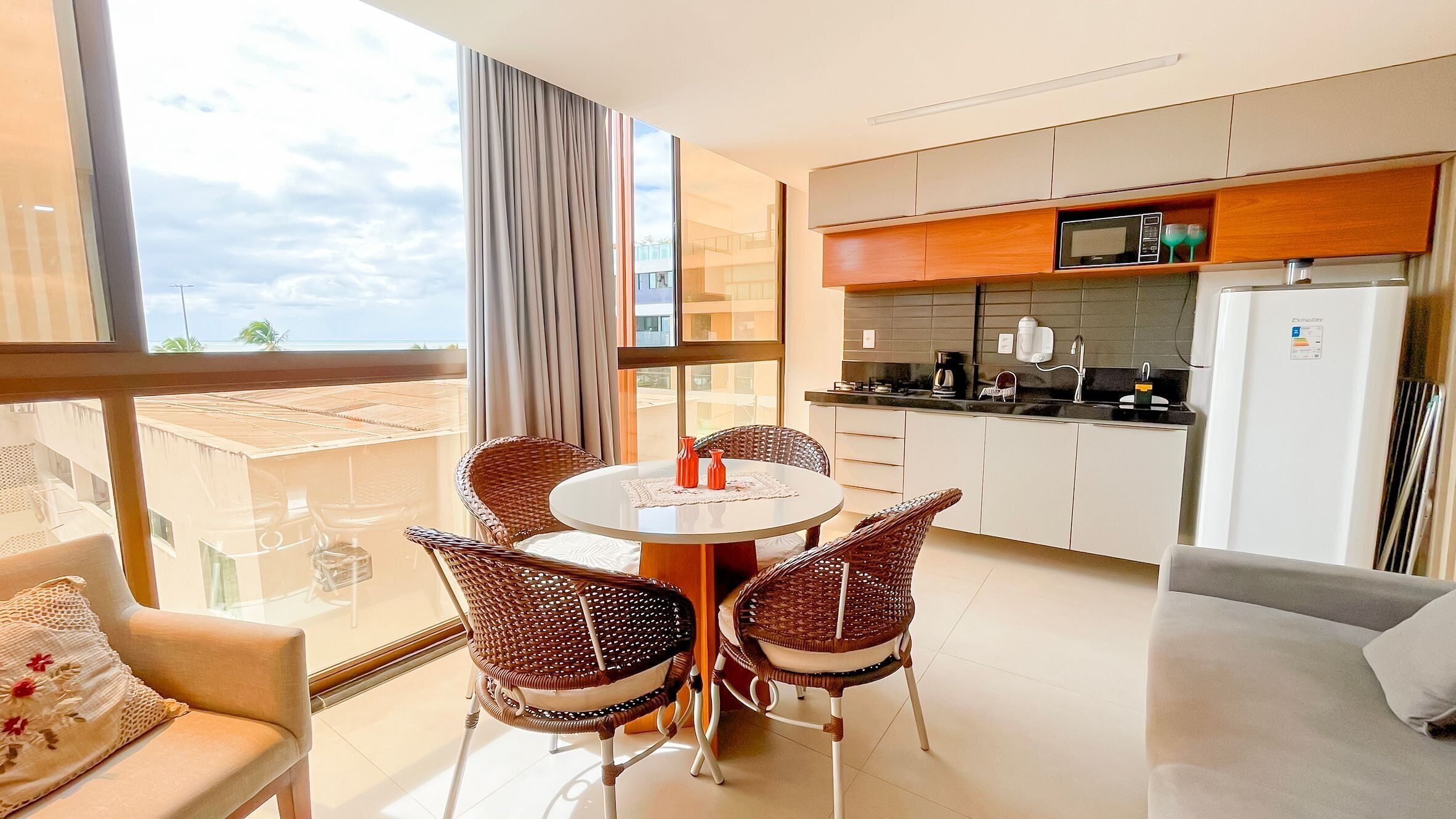 A modern kitchen with a dining area, large windows, and a view of the outdoors.