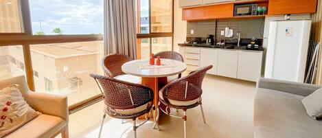 A modern kitchen with a dining area, large windows, and a view of the outdoors.