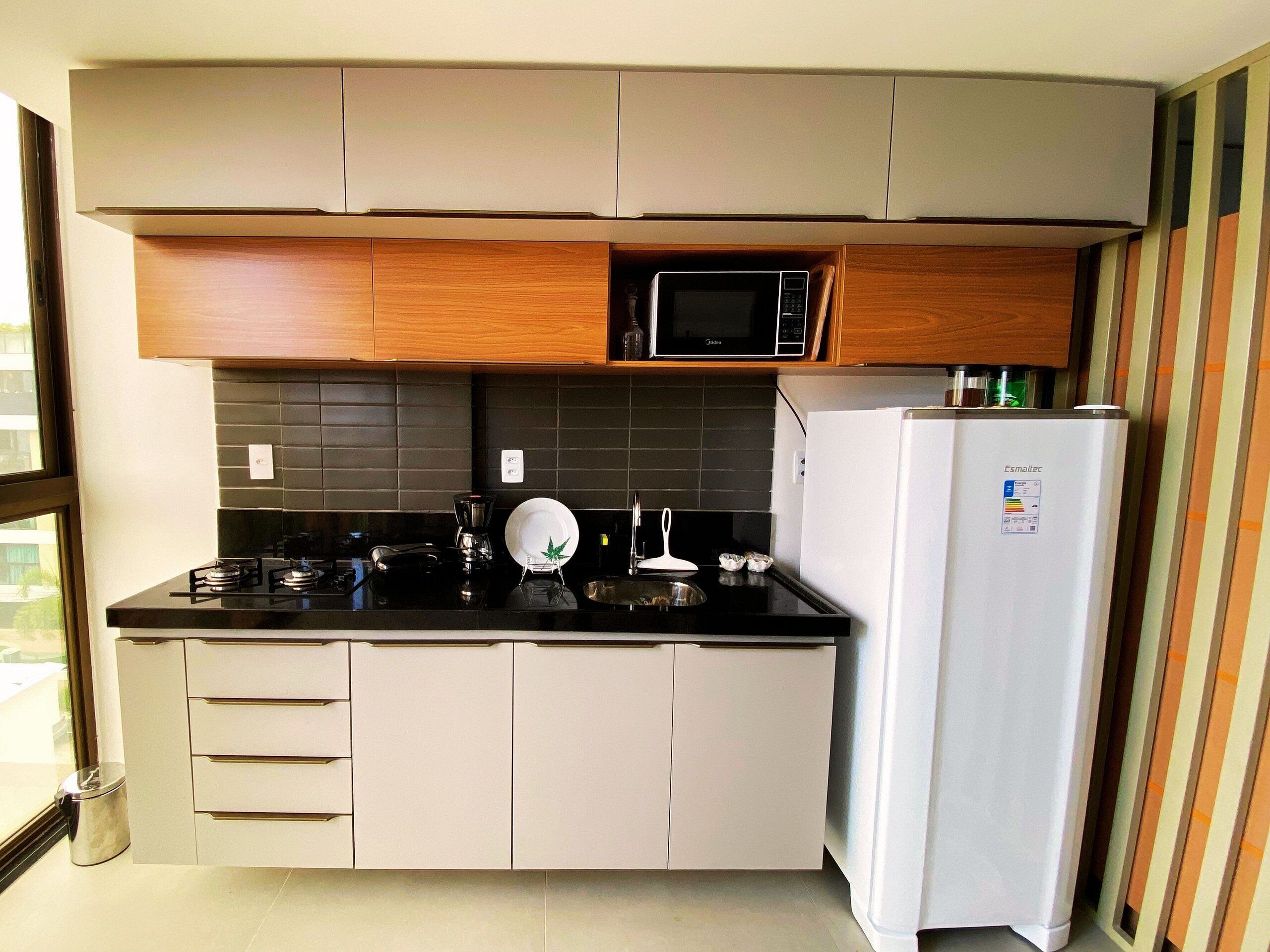 A compact kitchen with a microwave, a coffee maker, and a refrigerator.