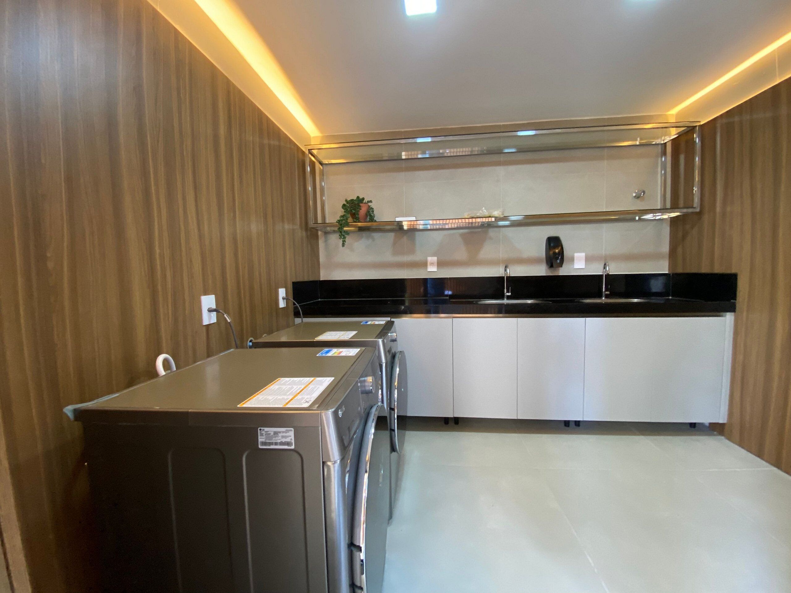 A modern kitchen with a stainless steel refrigerator, a black countertop, and white cabinets.