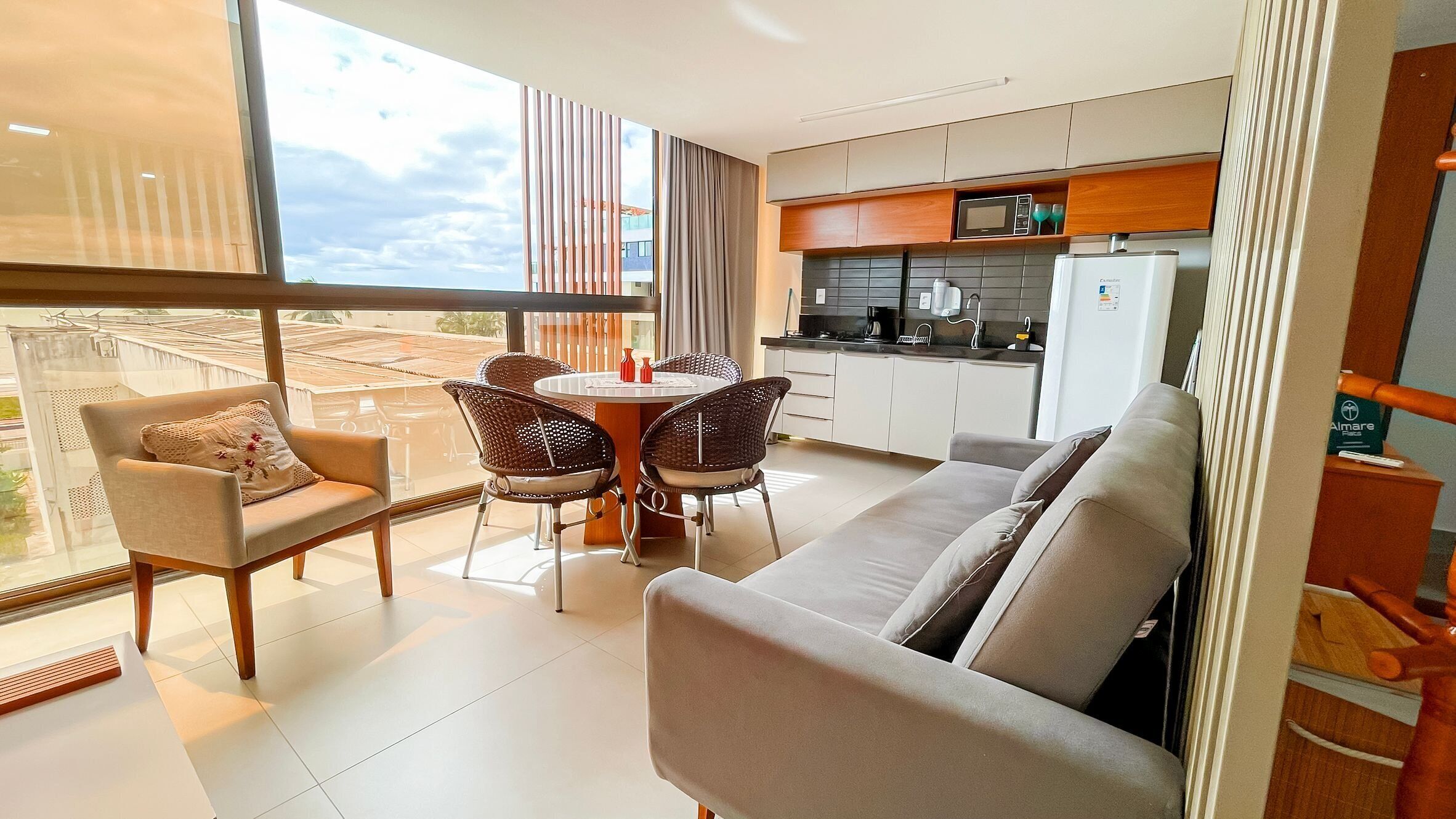 A modern living room with a sofa, two chairs, a dining table, and a kitchen area with a microwave and cabinets.