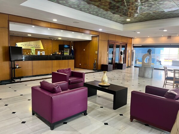 A lobby with purple sofas, a reception desk, and a view of the outside. - Intercity Tower Hotels  (San Pedro Sula)