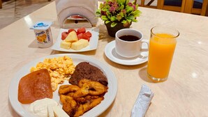 A dining table with a plate of food, a cup of coffee, a glass of orange juice, and a napkin. - Intercity Tower Hotels  (San Pedro Sula)