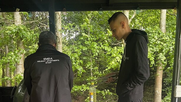 Two individuals at an outdoor dining area with a table set for a meal, surrounded by greenery. - EMDA country living close to Legoland. (Billund)