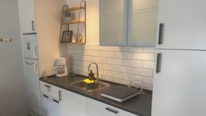 A modern kitchen with white cabinets, a black countertop, a coffee maker, and a sink. - EMDA country living close to Legoland. (Billund)