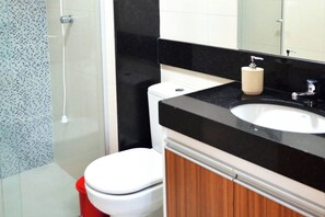 Bathroom features a large mirror, white sink, and shower area with a glass door.