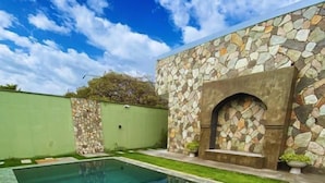 A swimming pool with stone walls and a stone fireplace. - Villas Gran (Paraipaba)