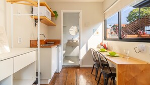 Eine kleine Küche mit einer Holzausziehtheke, einem Spülbecken und einem Fenster mit Blick auf eine Treppe.