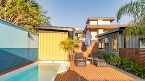 A swimming pool with a wooden deck, lounge chairs, and a covered seating area. - Parking|1000Mbps|A/C|Smart TV|Pool (Florianópolis)