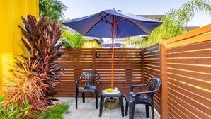 A patio area with a wooden fence, two chairs, a small round table, and a blue umbrella. - Parking|1000Mbps|A/C|Smart TV|Pool (Florianópolis)