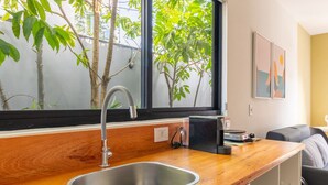 A modern kitchen with a stainless steel sink, wooden countertop, and a window with a view of trees. - SPA|A/C|BBQ|Container House°Full Kitchen° (Florianópolis)