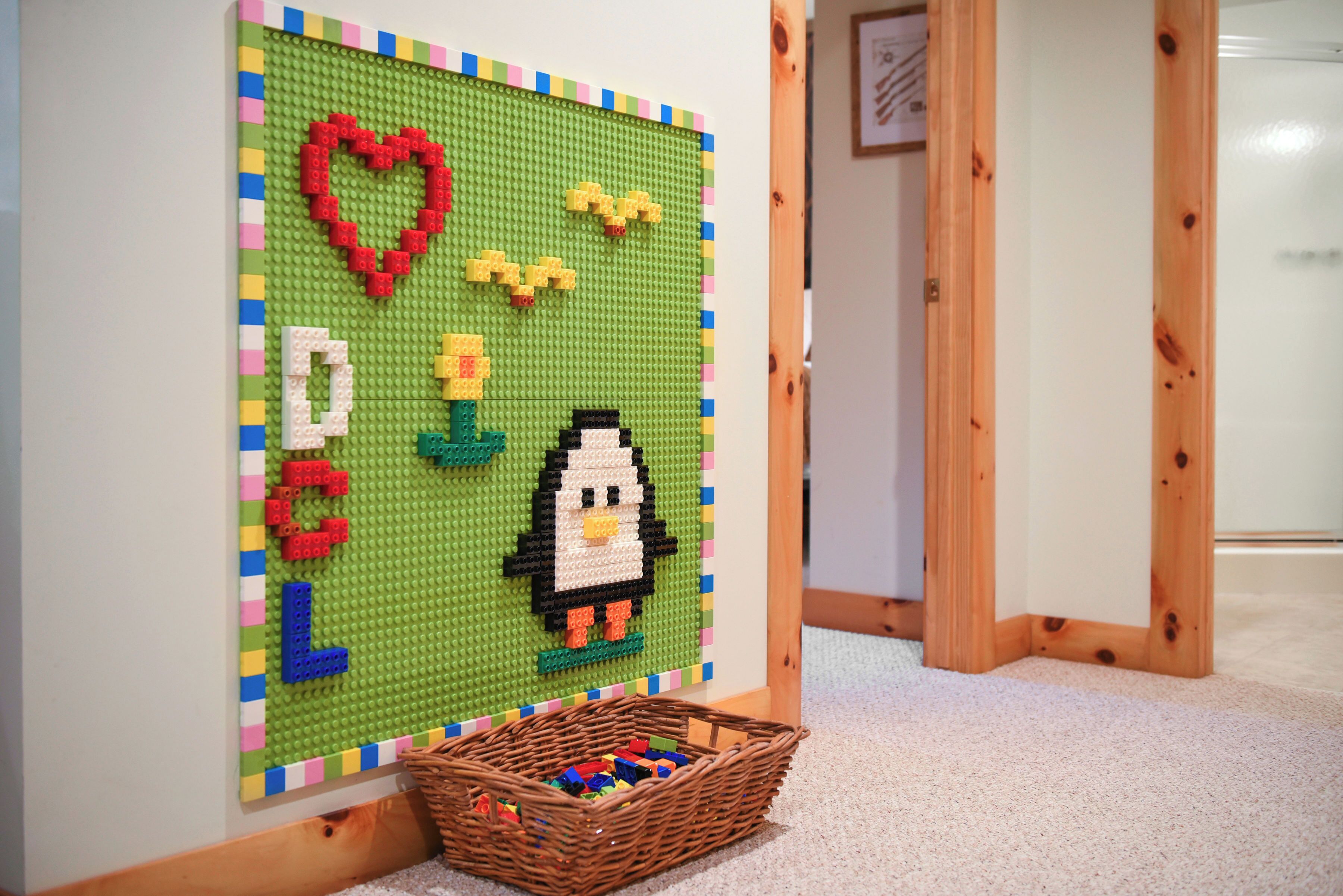 Una pared con una obra de arte de LEGO que presenta un corazón, letras y un pingüino.