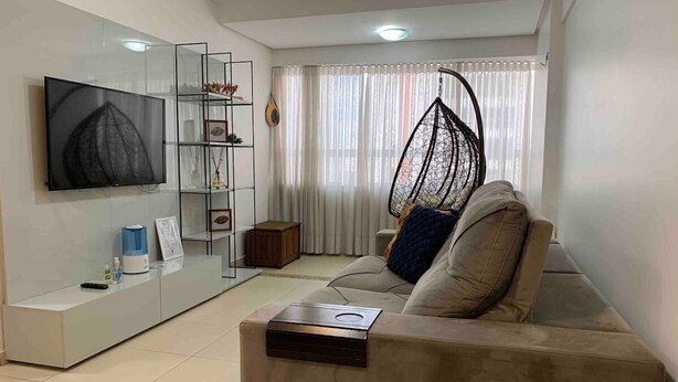 Een moderne woonkamer met een flatscreen televisie, een bank, een salontafel en een hangstoel.