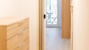 A wooden cabinet with drawers, a sliding glass door leading to a balcony with a table and chairs.