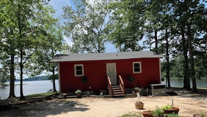 A red cabin with a wooden deck, surrounded by potted plants and a bench, overlooking a lake. - Lakefront spectacular view 

























 (Henrico)