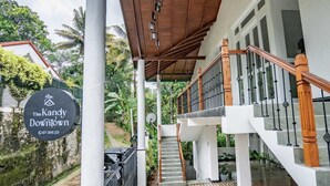 Un espacio al aire libre cubierto con una escalera que conduce a un segundo piso, rodeado de follaje.