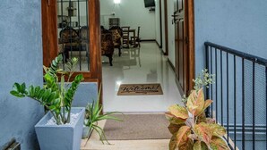 Una entrada limpia y moderna con puerta de madera, felpudo y plantas en macetas.