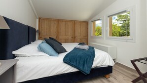 Ein Schlafzimmer mit Bett, Holzschrank, Fenster und Heizkörper.
