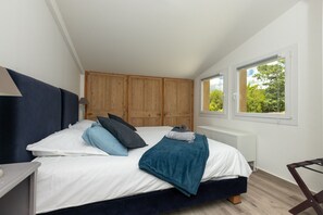 A bedroom with a bed, wooden wardrobe, window, and radiator.