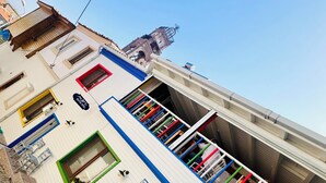 Un edificio de varios pisos con fachada blanca, detalles azules y varios balcones.