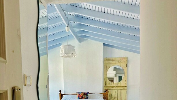 Un dormitorio con cama de madera, techo blanco y suelo de madera.